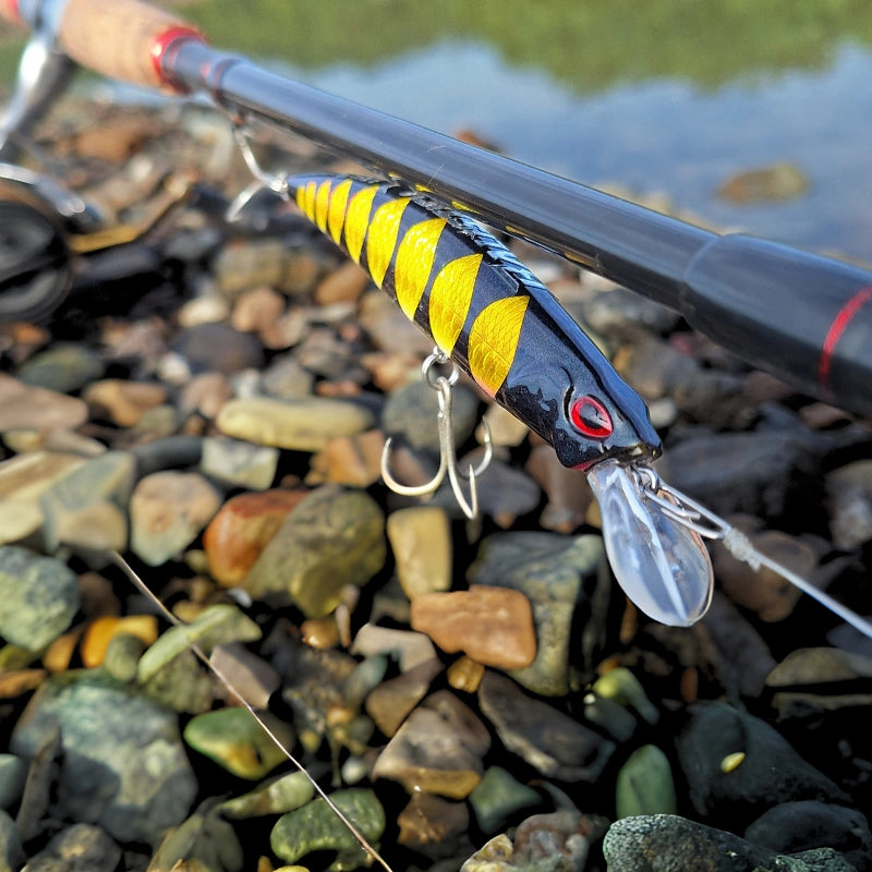 Beautiful black and gold minnow jerkbait fishing lure on a fishing rod with estury in the background.