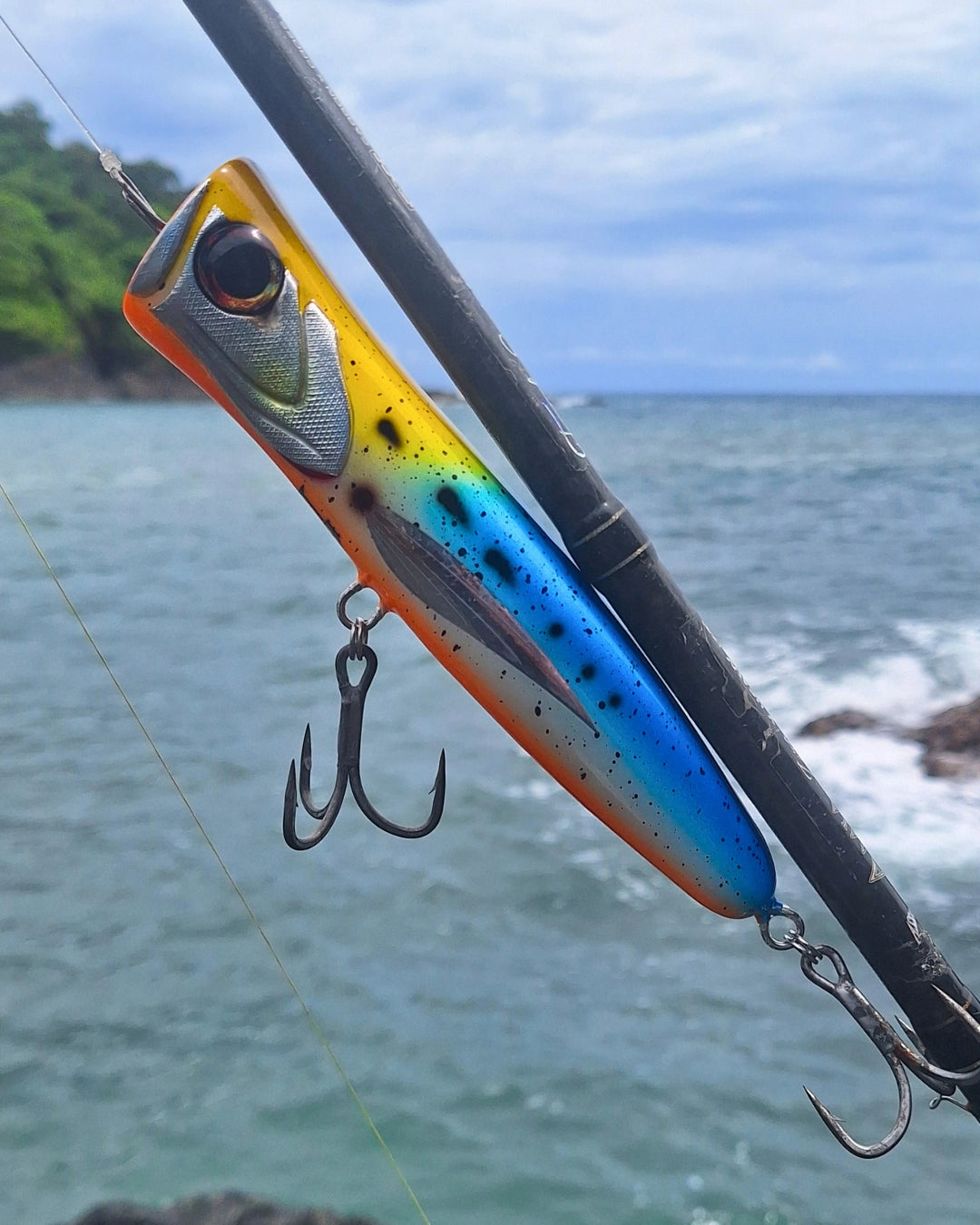 Blue and Yellow premium handcrafted surface popper with ocean in the background.